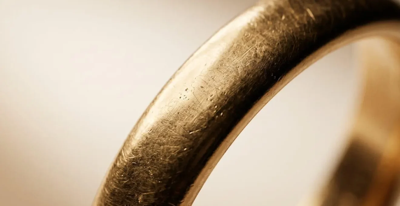 Gros plan macro d'une alliance en or 18 carats révélant sa texture et son éclat profond