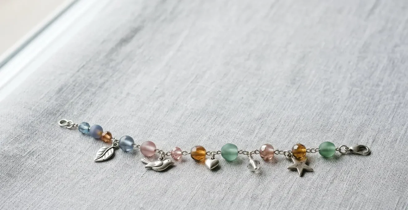 Composition harmonieuse d'un bracelet à charms avec perles de verre colorées et charms en argent arrangés avec équilibre visuel