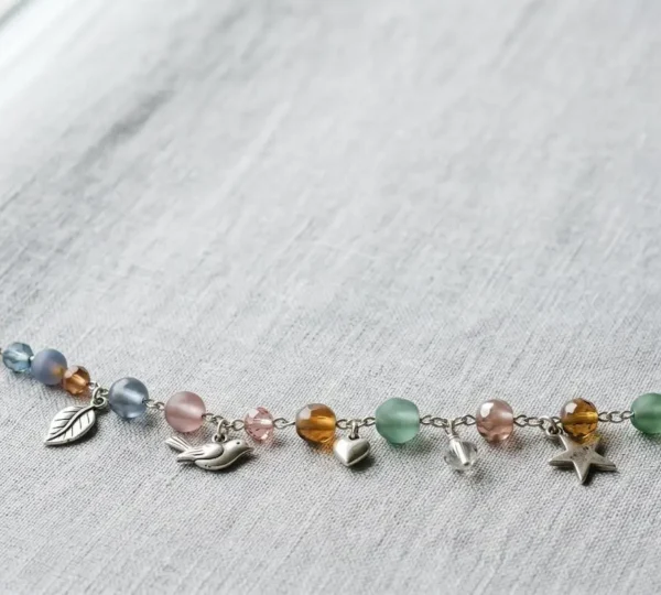 Composition harmonieuse d'un bracelet à charms avec perles de verre colorées et charms en argent arrangés avec équilibre visuel