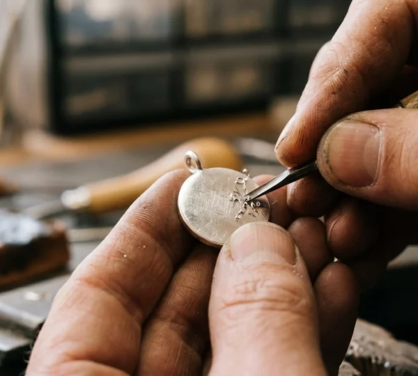 Atelier de gravure artisanale sur pendentif avec outils de bijoutier