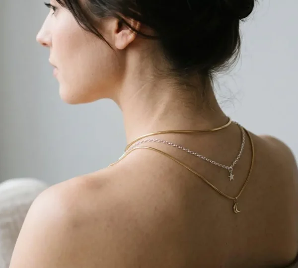 Superposition élégante de plusieurs colliers fins de différentes longueurs sur une nuque féminine