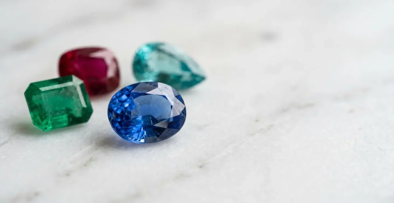 Gros plan sur une collection de pierres précieuses colorées aux duretés variées disposées sur une surface neutre