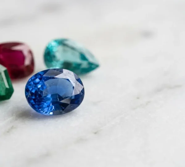 Gros plan sur une collection de pierres précieuses colorées aux duretés variées disposées sur une surface neutre