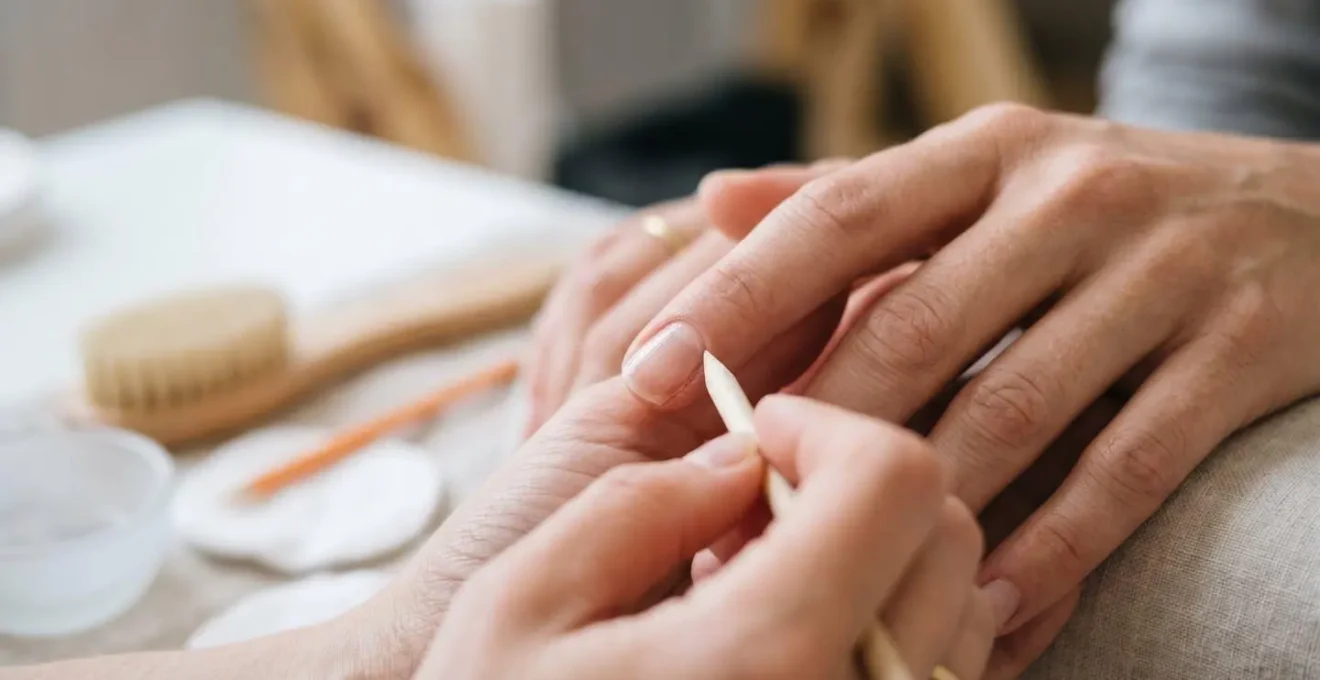 Gros plan macro sur des ongles féminins en cours de soin, montrant des mains élégantes dans un environnement professionnel de manucure, éclairage naturel doux