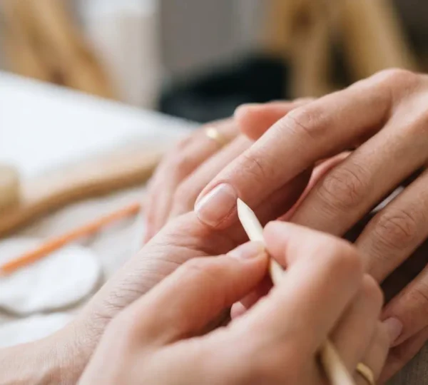 Gros plan macro sur des ongles féminins en cours de soin, montrant des mains élégantes dans un environnement professionnel de manucure, éclairage naturel doux